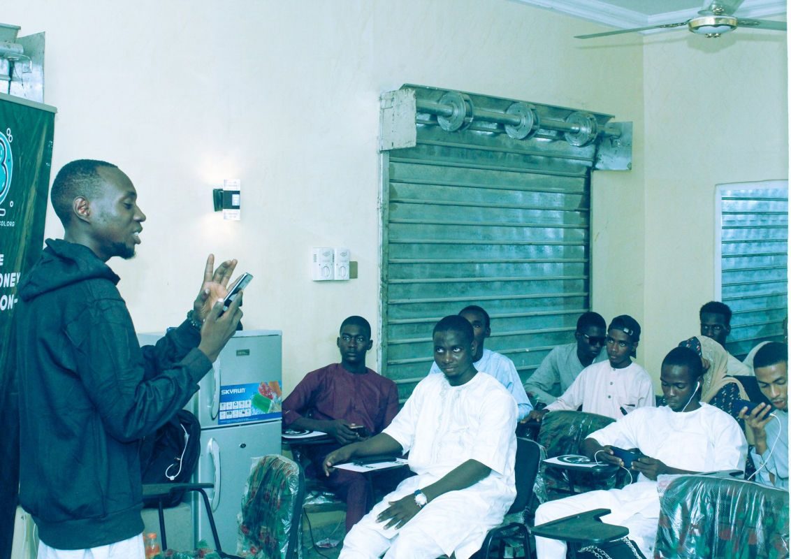 A facilitator speaking to a seated group at a campus meetup