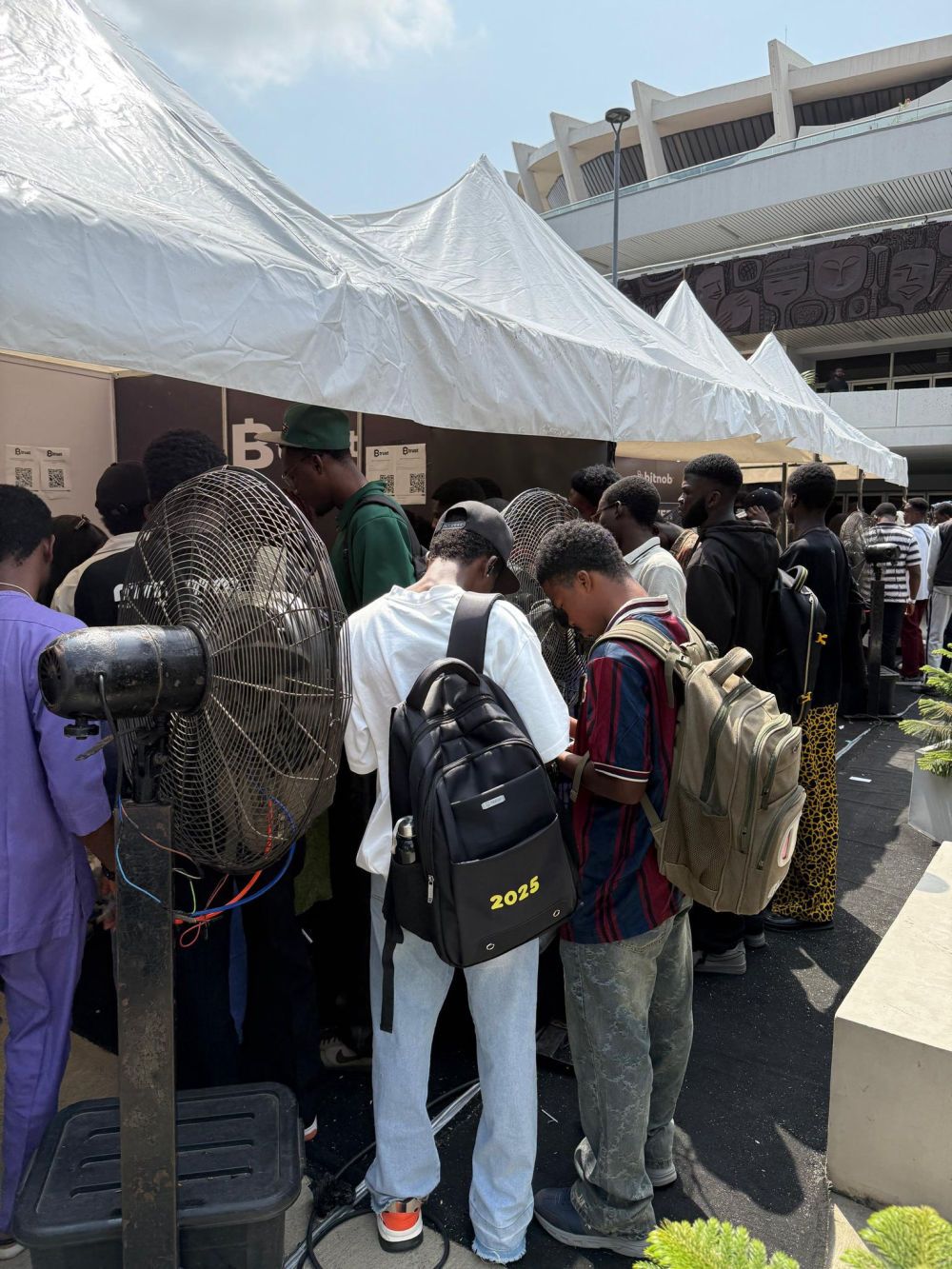 A crowd of students gathered under tents at an outdoor event