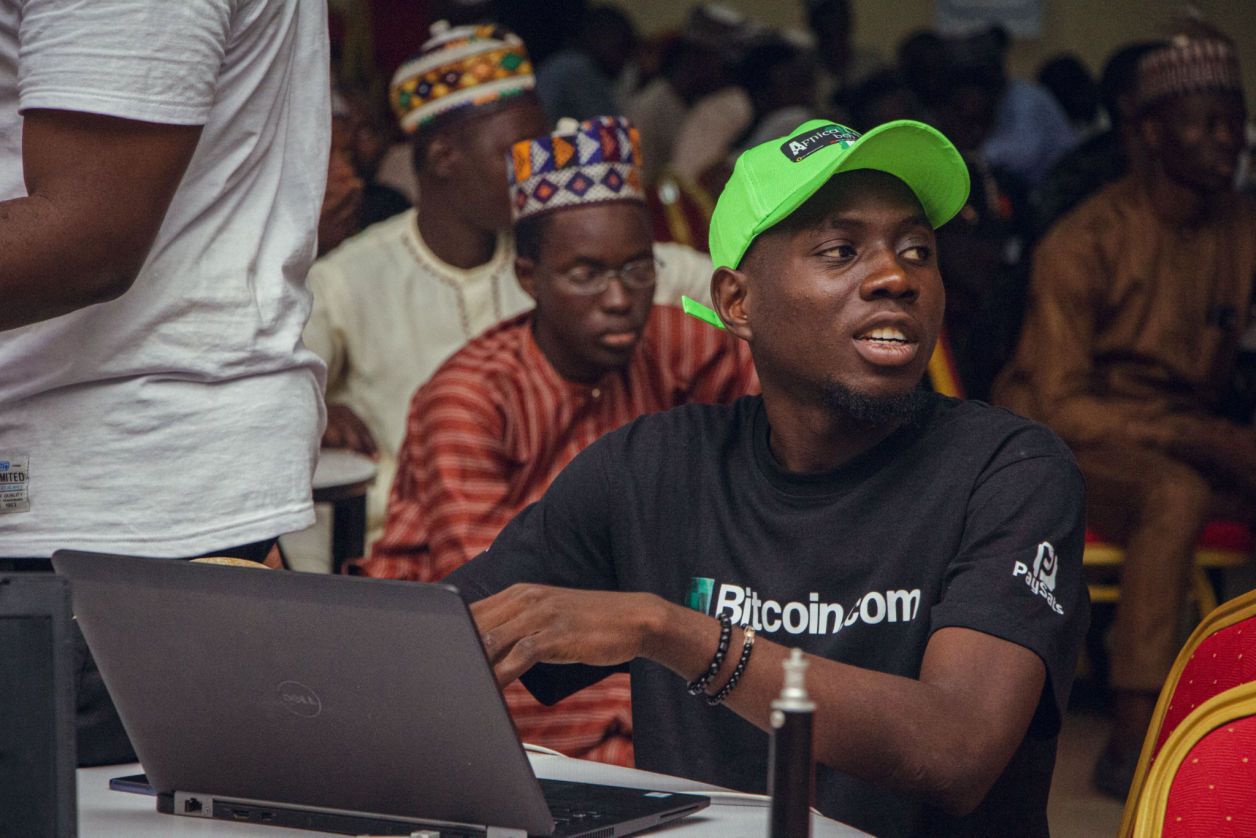 A participant in a green cap working on a laptop